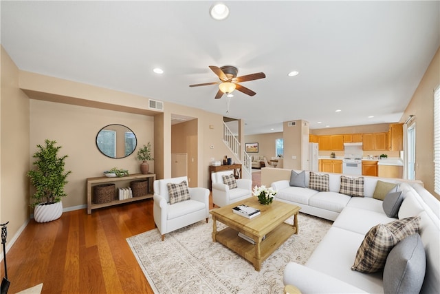 living room featuring light wood-type flooring, ceiling fan, and plenty of natural light