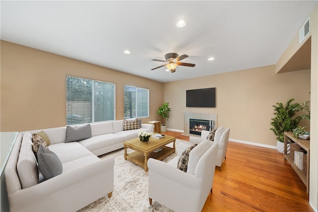 living room featuring light wood-type flooring, a fireplace, and ceiling fan