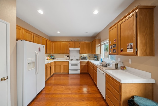 kitchen with tile counters, light hardwood / wood-style floors, and white appliances