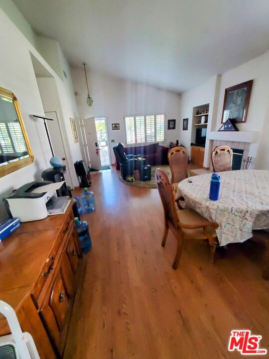 dining room featuring hardwood / wood-style floors, a tiled fireplace, and vaulted ceiling