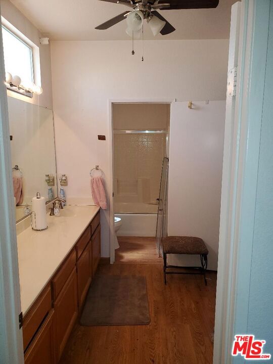 full bathroom with vanity, toilet, wood-type flooring, and bath / shower combo with glass door