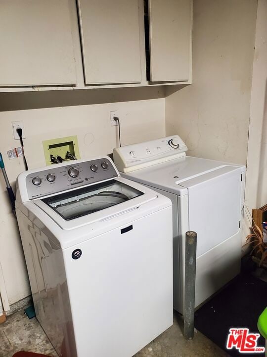 washroom with washer and dryer and cabinets