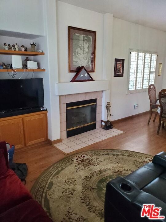 living room featuring a tile fireplace and light hardwood / wood-style flooring