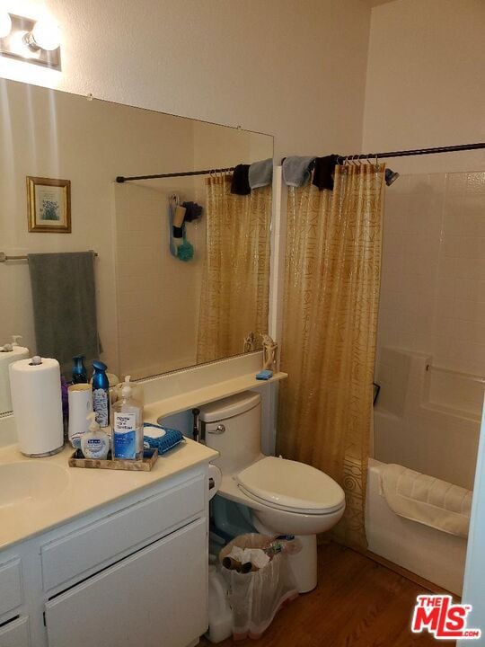 full bathroom with hardwood / wood-style floors, vanity, toilet, and shower / bath combo with shower curtain