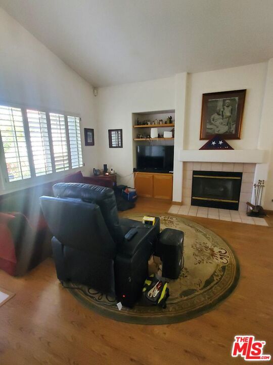 living room with vaulted ceiling and a tiled fireplace