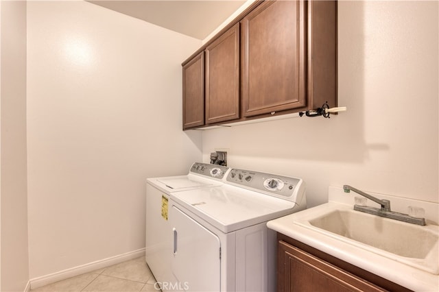 laundry area with cabinets, light tile patterned flooring, washer and dryer, and sink