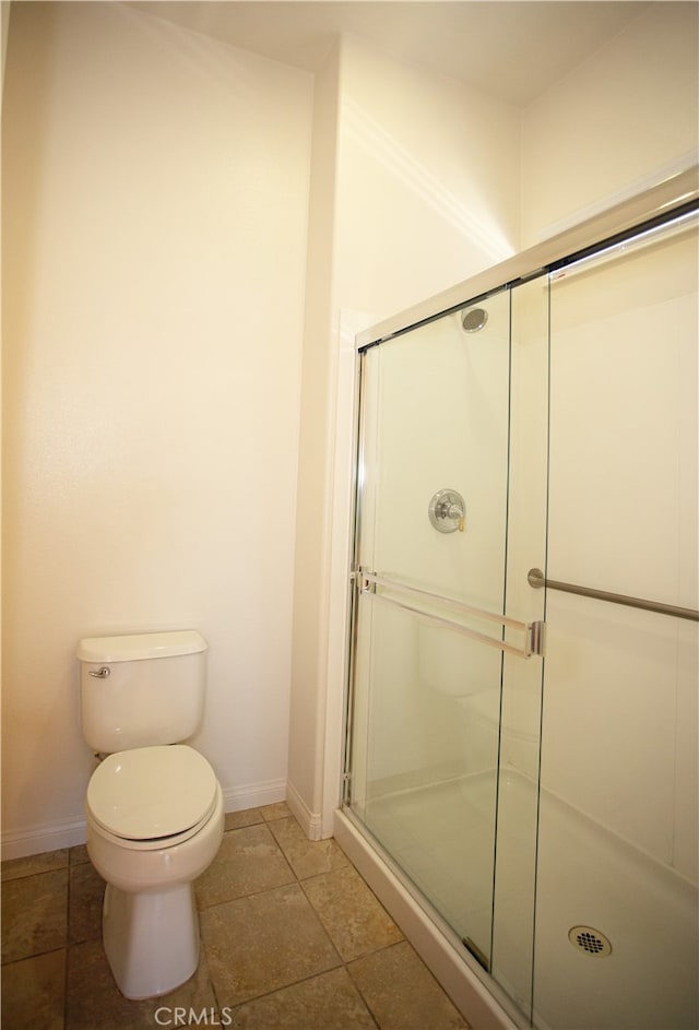 bathroom with a shower with shower door, toilet, and tile patterned floors