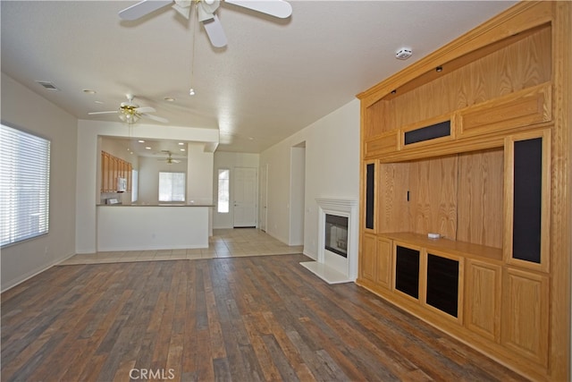 unfurnished living room featuring dark hardwood / wood-style floors, ceiling fan, and a wealth of natural light