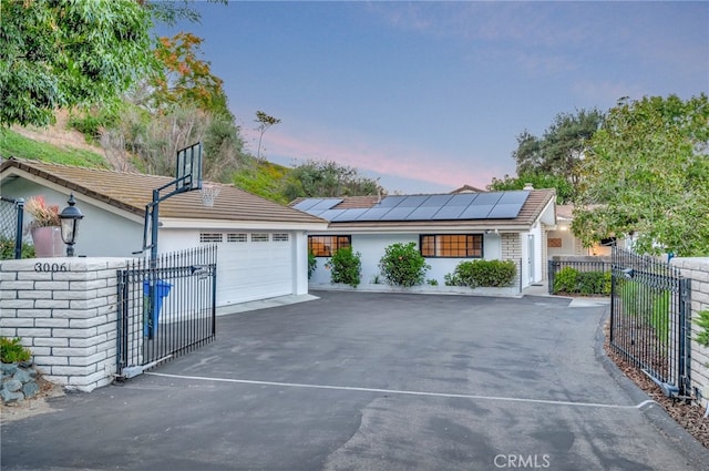 ranch-style home with solar panels and a garage