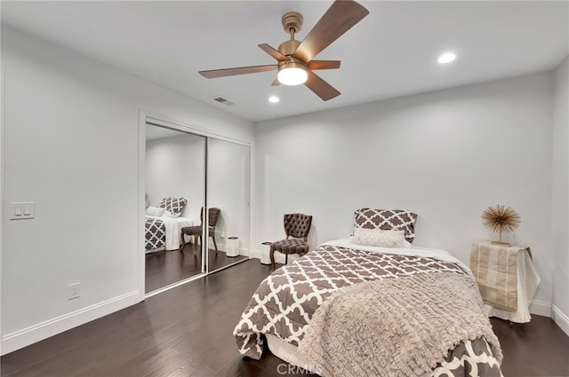 bedroom with dark wood-type flooring, ceiling fan, and a closet