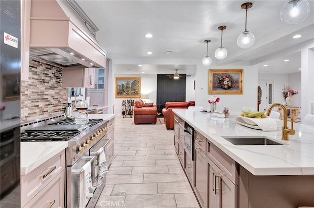 kitchen with light stone counters, sink, decorative light fixtures, ceiling fan, and stainless steel range