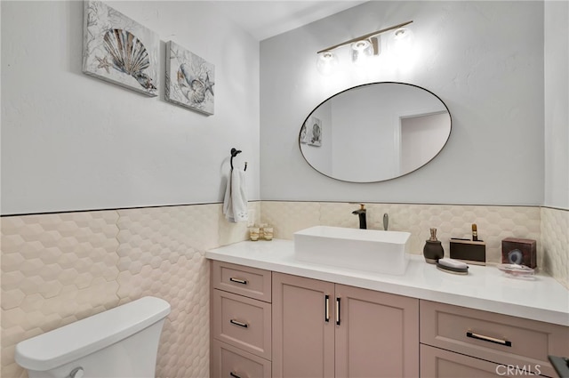 bathroom featuring tile walls, vanity, and toilet