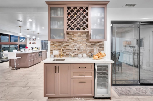 kitchen with decorative backsplash, a kitchen bar, beverage cooler, decorative light fixtures, and sink