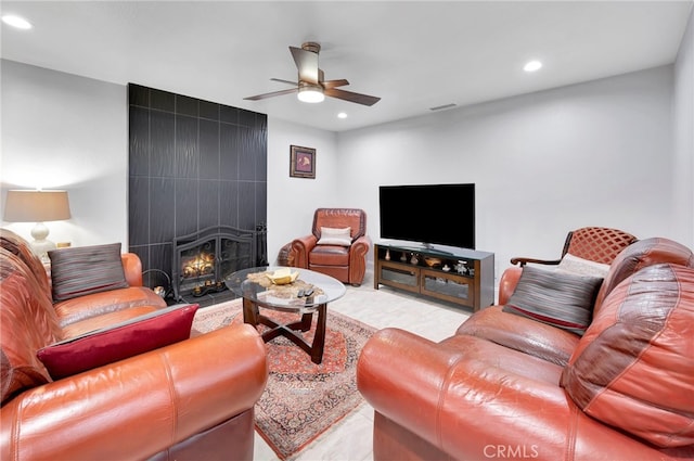 living room with a tile fireplace and ceiling fan