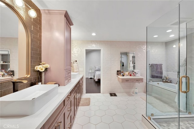 bathroom with plus walk in shower, tile walls, tile patterned floors, and vanity