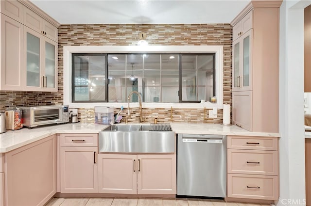 kitchen with light stone counters, sink, decorative backsplash, light tile patterned floors, and stainless steel dishwasher