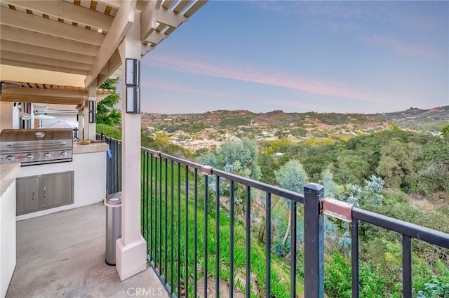 balcony at dusk with exterior kitchen and a grill