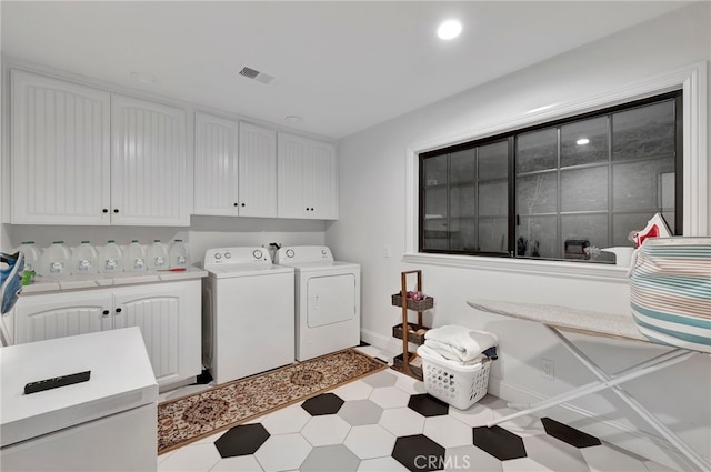 clothes washing area featuring washing machine and dryer and cabinets