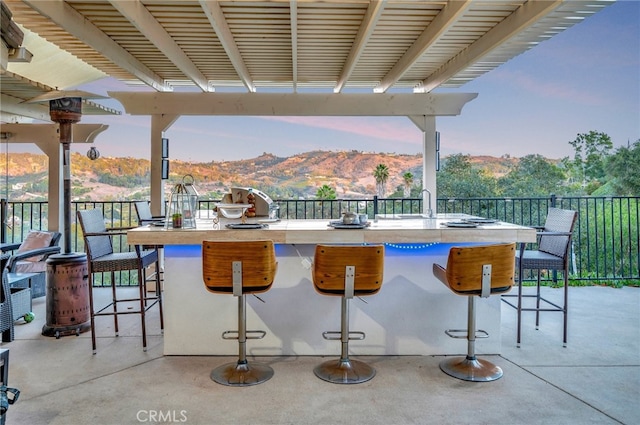 patio terrace at dusk with a mountain view and a bar