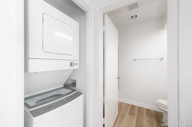 laundry area featuring stacked washer / drying machine and light hardwood / wood-style floors