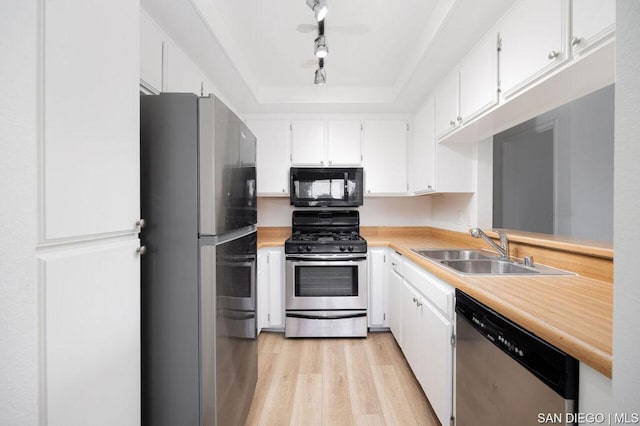 kitchen with light wood-type flooring, appliances with stainless steel finishes, white cabinetry, and sink