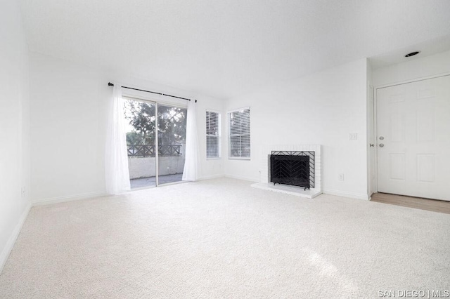 unfurnished living room with light colored carpet and a fireplace