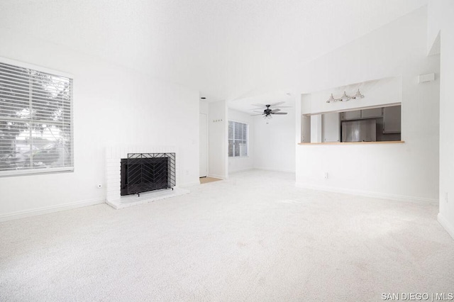 unfurnished living room with a brick fireplace, ceiling fan, and carpet flooring