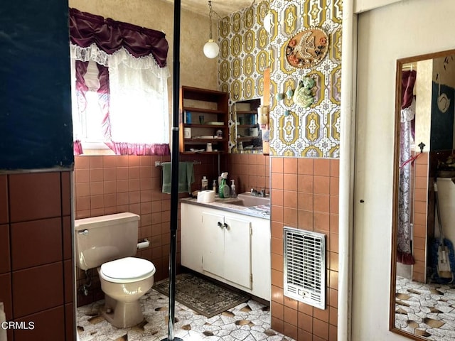 bathroom featuring tile walls, vanity, heating unit, and toilet