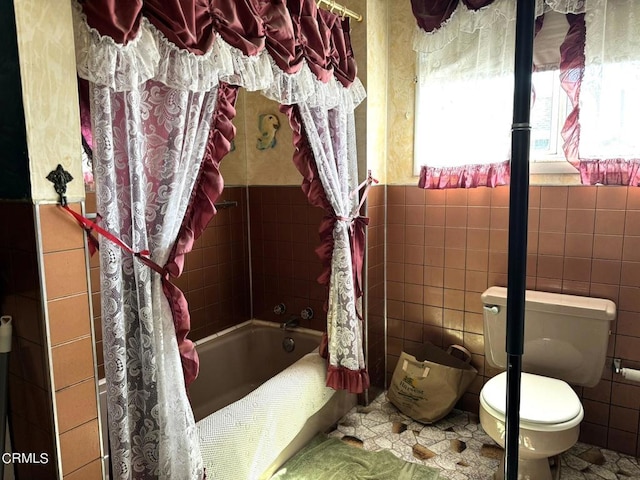 bathroom featuring tile walls, shower / bathtub combination with curtain, and toilet