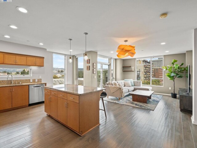 kitchen with dark hardwood / wood-style floors, dishwasher, hanging light fixtures, a kitchen island, and sink