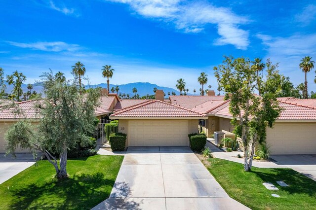 view of front facade with a mountain view, a front yard, and a garage