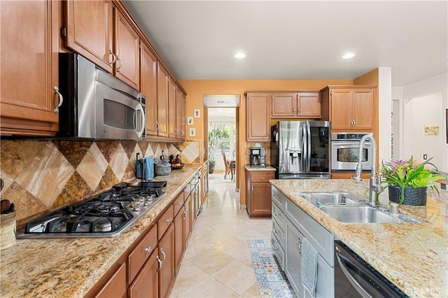 kitchen with light tile patterned flooring, sink, light stone counters, stainless steel appliances, and backsplash