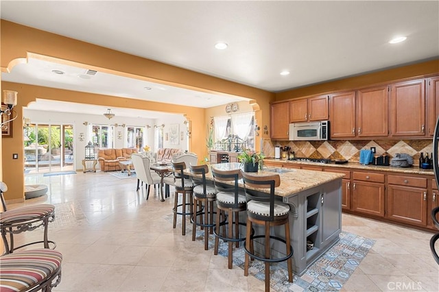 kitchen with stainless steel appliances, a breakfast bar area, a center island, a healthy amount of sunlight, and decorative backsplash