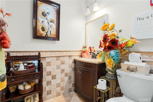 bathroom with vanity, toilet, and tile walls