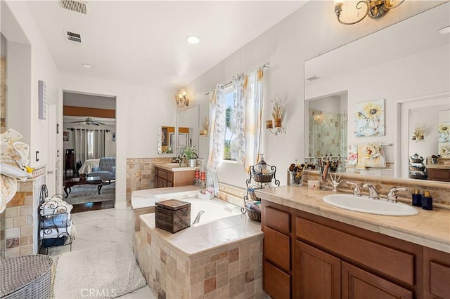 bathroom featuring a relaxing tiled tub, ceiling fan, and vanity