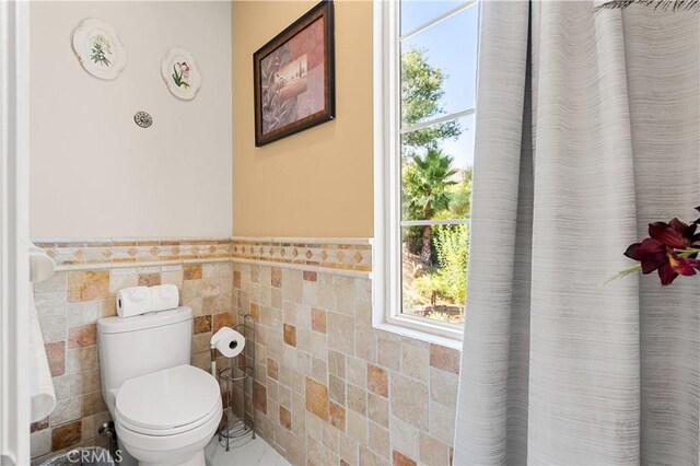 bathroom featuring tile walls and toilet