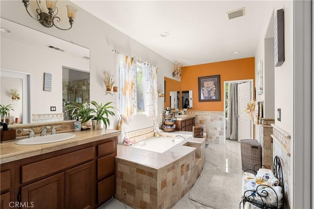 bathroom featuring vanity, tiled tub, and a notable chandelier