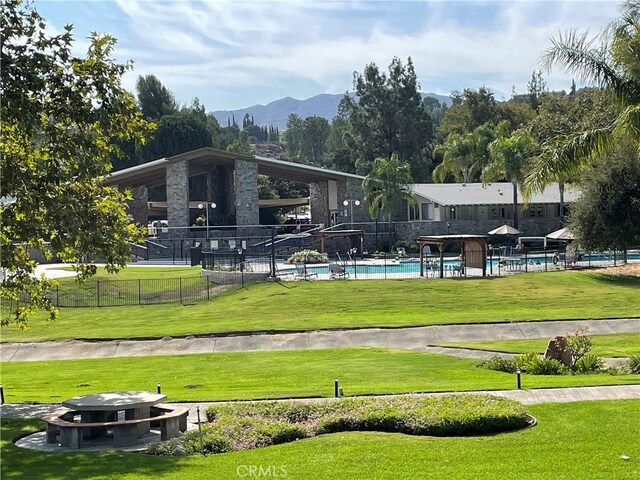 surrounding community featuring a mountain view, a pool, and a lawn