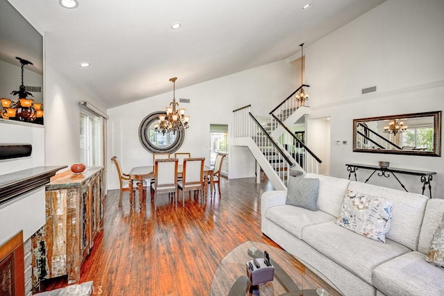 living room with a wealth of natural light, dark hardwood / wood-style floors, vaulted ceiling, and a notable chandelier