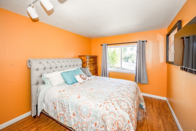 bedroom featuring hardwood / wood-style floors and track lighting