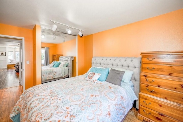 bedroom featuring hardwood / wood-style flooring and track lighting