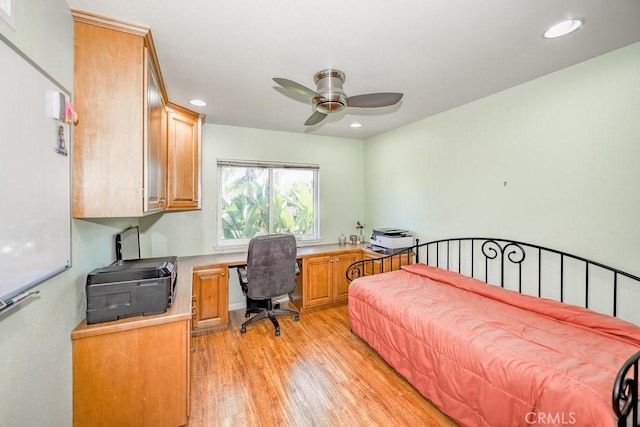 bedroom with ceiling fan, built in desk, and light hardwood / wood-style flooring