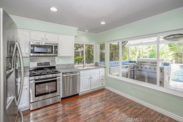 kitchen featuring appliances with stainless steel finishes, dark hardwood / wood-style flooring, crown molding, sink, and white cabinetry