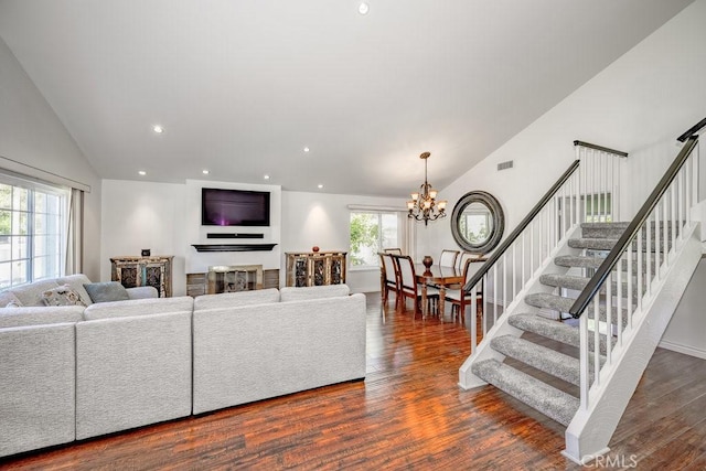 living room with a wealth of natural light, dark wood-type flooring, lofted ceiling, and a notable chandelier