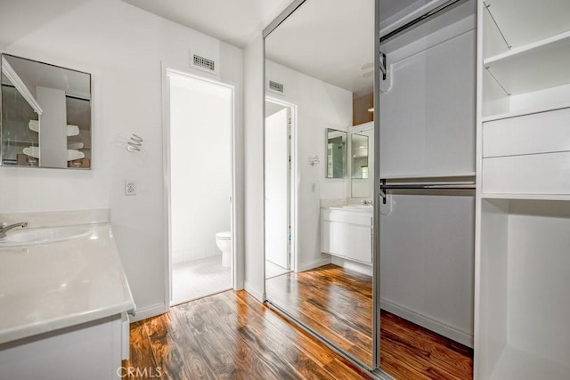 bathroom with hardwood / wood-style floors, vanity, and toilet