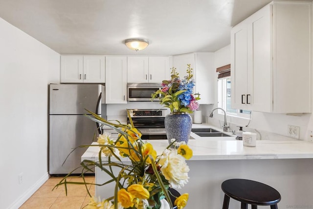 kitchen featuring light tile patterned flooring, white cabinetry, stainless steel appliances, and kitchen peninsula