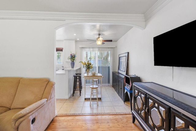 living room with light hardwood / wood-style floors, ornamental molding, and ceiling fan