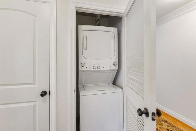 clothes washing area with stacked washer and dryer, hardwood / wood-style floors, and crown molding