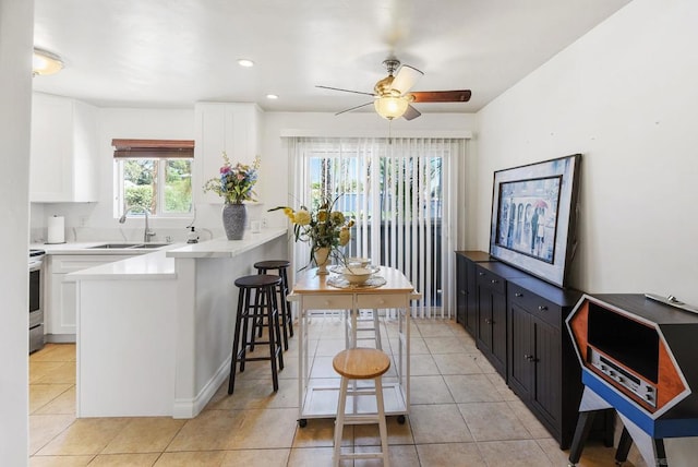 kitchen with sink, white cabinets, kitchen peninsula, a kitchen breakfast bar, and ceiling fan