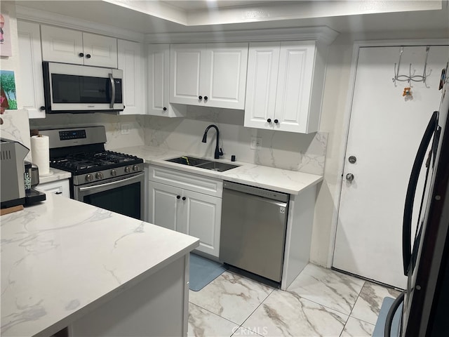 kitchen featuring sink, white cabinetry, backsplash, appliances with stainless steel finishes, and light stone countertops